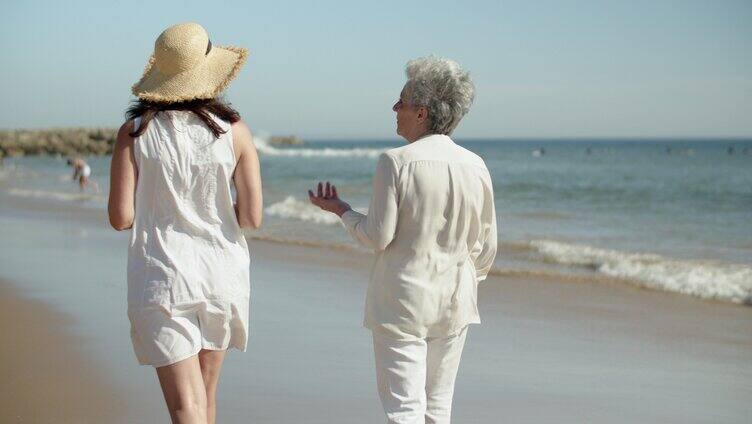 年轻女孩和妈妈在海边散步聊天