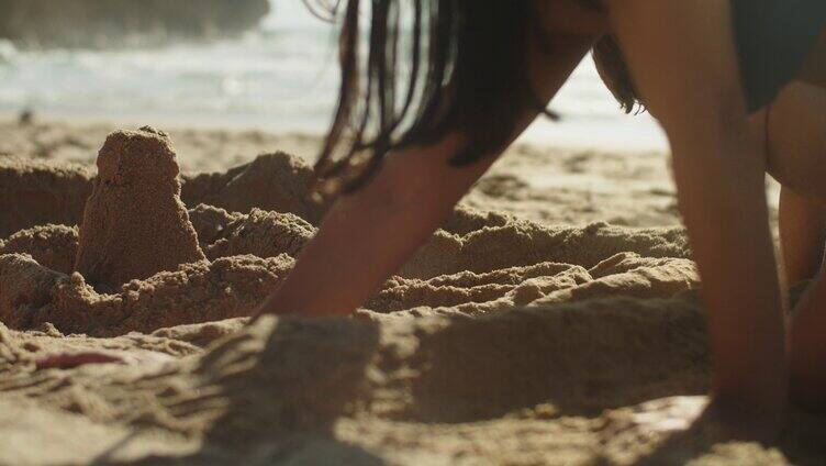 一个女孩在沙滩上挖沙堆沙人