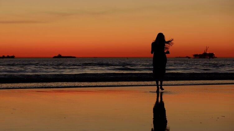 女子在海边沙滩夕阳下奔跑背影