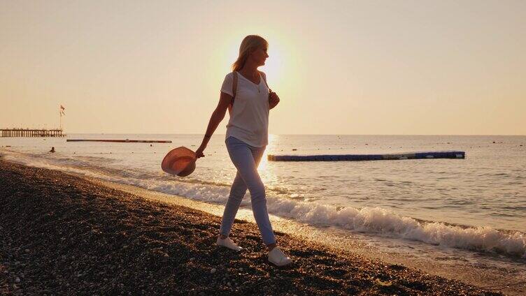 夕阳下海边漫步的美丽女子