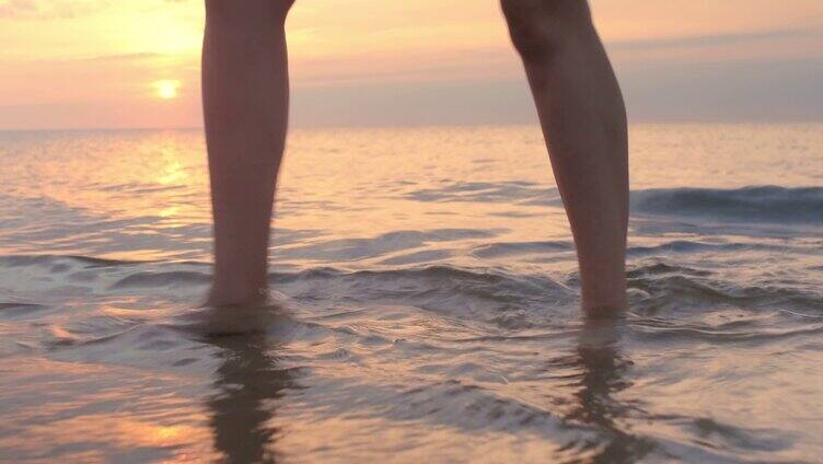落日余晖下在海滩上赤脚行走