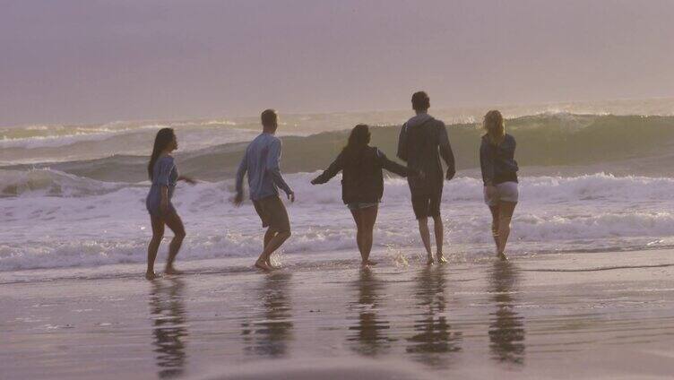 一群人享受暑假在沙滩跑步