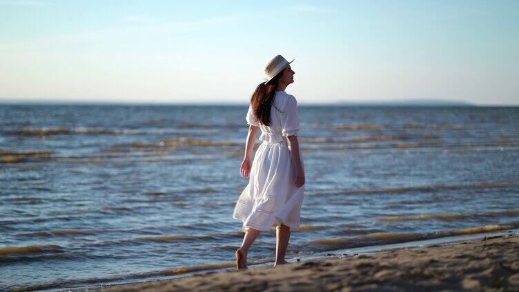 沿着沙滩行走的白裙女子特写