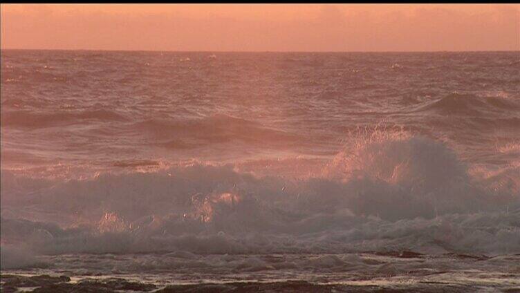 夕阳下碧蓝海浪冲击沙滩