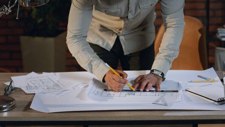建筑师在桌子上的大纸上绘制建筑平面图的俯