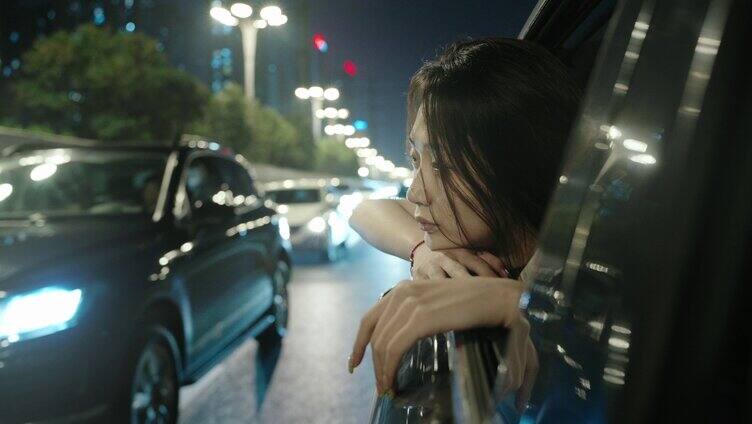 城市路灯下年轻的女性靠在车窗上情绪低落。
