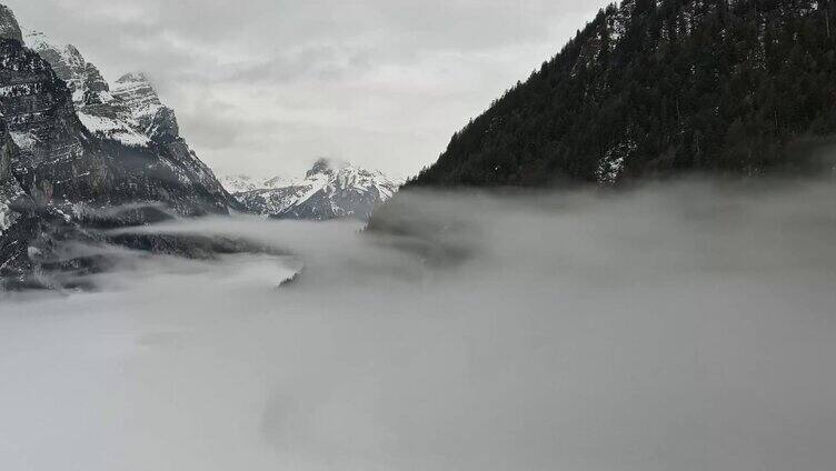 被雪覆盖的山峰之间云雾飘绕冰面寒流雾气