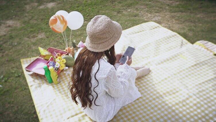 4K唯美小清新少女野餐垫上玩手机实拍