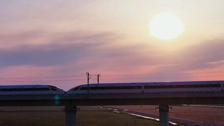 高铁列车行驶广袤田野 夕阳下的高铁列车