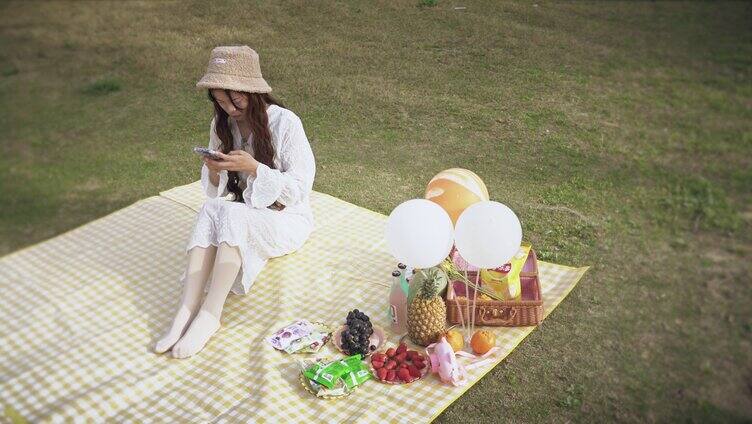 4K实拍少女坐在野餐垫玩手机实拍视频