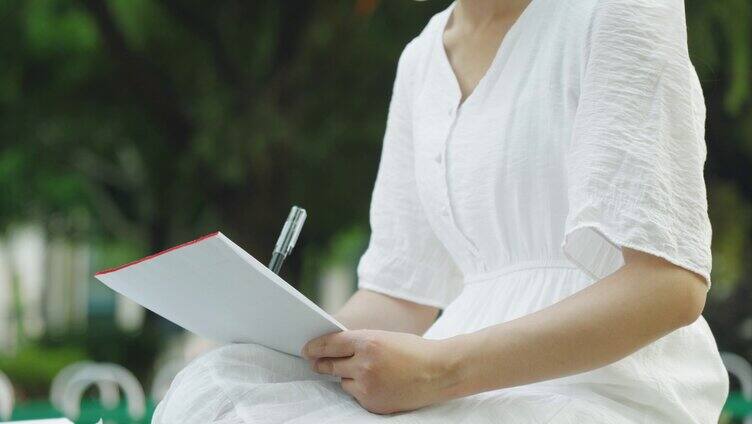 美女在公园拿笔写信记录 写信的女人
