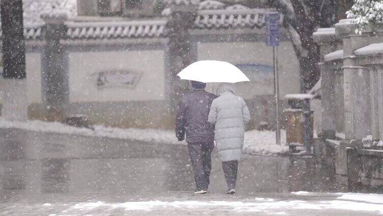 下雪天老年夫妻手挽手走路背影