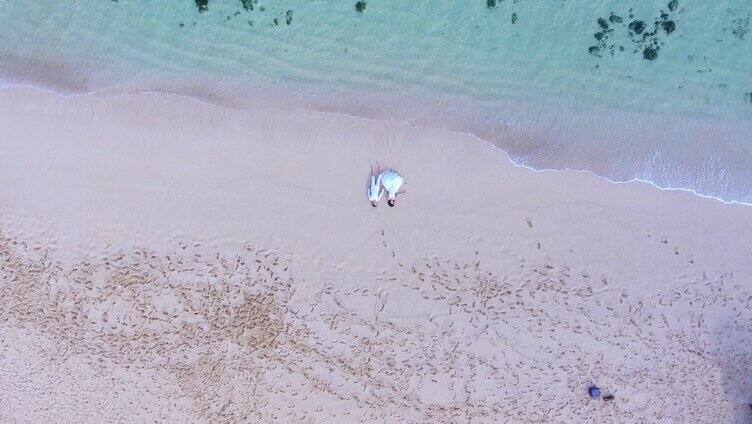 俯拍情侣穿婚纱照躺在沙滩上浪漫