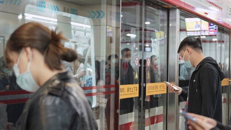 地铁进站行驶乘客低头看手机等车
