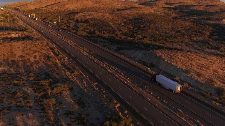 图片:夏日日落时分，汽车和半卡车在繁忙的高速公路上行驶