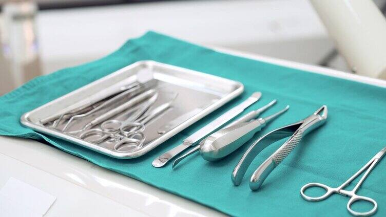 清理:无菌牙科器械、手术剪刀、钳子、牙根提升器、骨膜，在绿色无菌布上为牙科医生准备