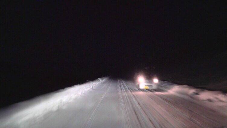 晚上在森林里的雪路上开车。