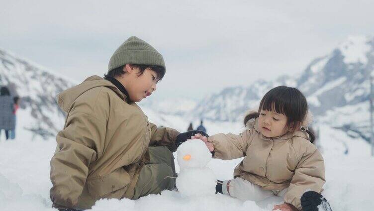 俩个小孩在雪地堆雪人