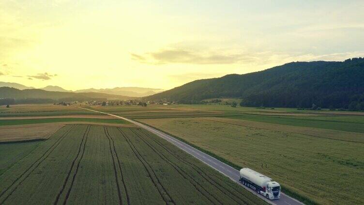 油罐车行驶在公路上，穿过风景如画的田野自然航拍