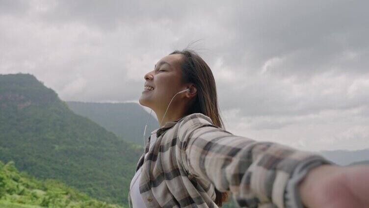 年轻女子张开双臂欣赏风景