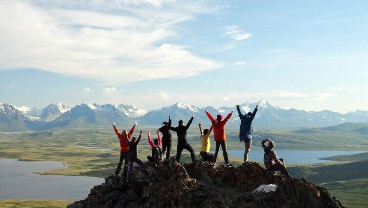 旅行团一起在山顶上举起手，欢呼成就后景