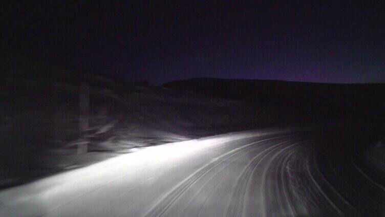 晚上在森林里的雪路上开车。
