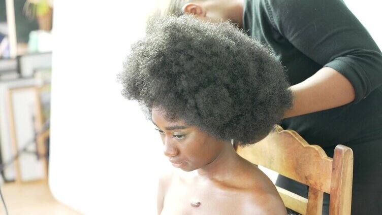 一位年轻女子正在沙龙里调整她的非洲式假发