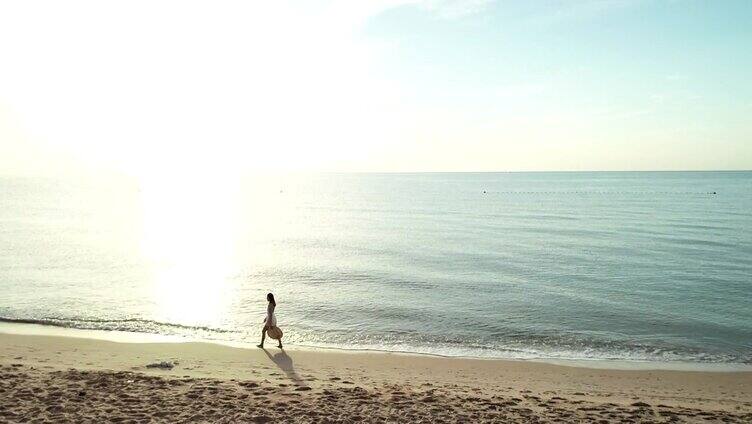 无人机航拍，年轻女子走在海滩上。