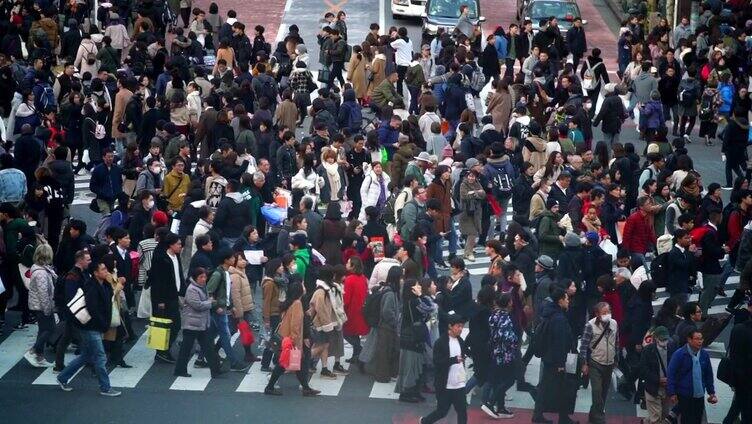 慢镜头城市景观和城市生活的亚洲拥挤的行人，男人和女人与游客步行穿过涩谷十字路口的红绿灯人行横道，东京市，日本