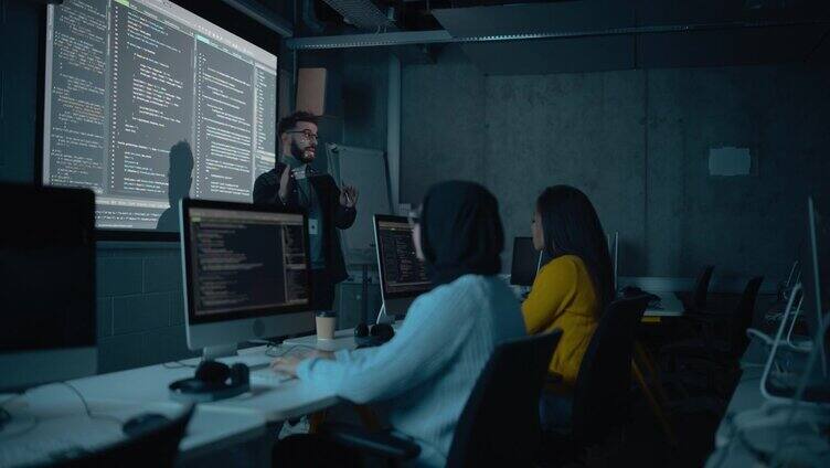 教师在黑暗的大学教室里给多元的多民族男女学生讲授计算机科学。放映幻灯片与编程代码。解释信息技术。