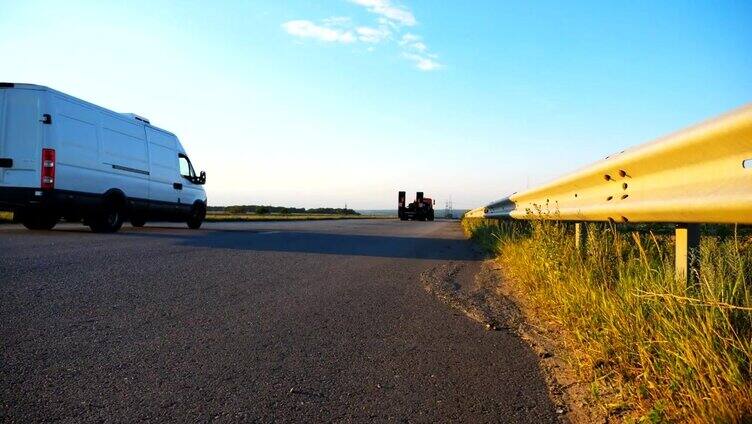 摄像机跟随卡车在乡村公路上行驶。卡车驶过乡村，后面是美丽的风景。乡村公路的景色。慢动作