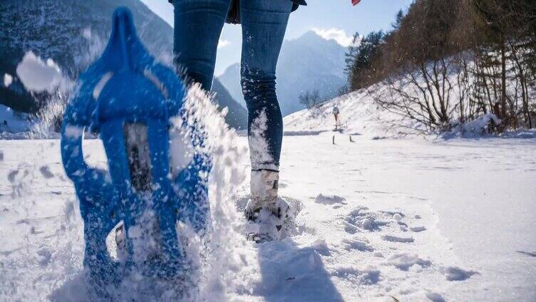 在新雪上穿雪鞋行走的女人