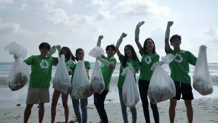 一群快乐的志愿者用垃圾袋清理海滩上的区域。志愿、慈善、清洁、人与生态的观念