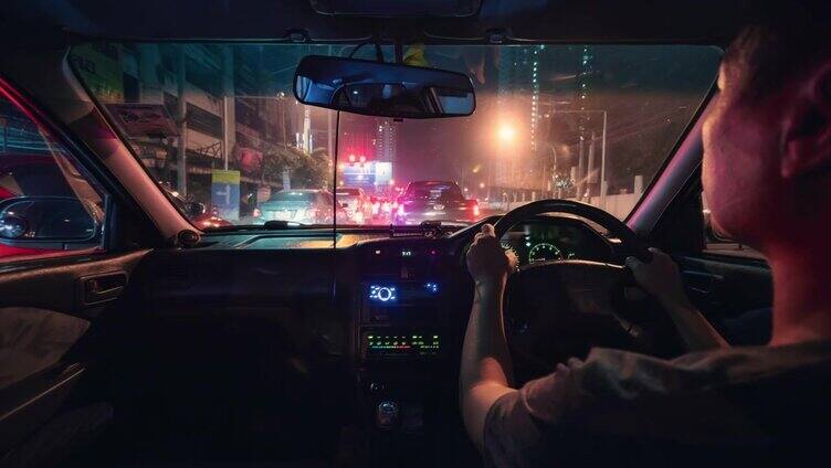 一个男人开着车在夜间城市的路上旅行