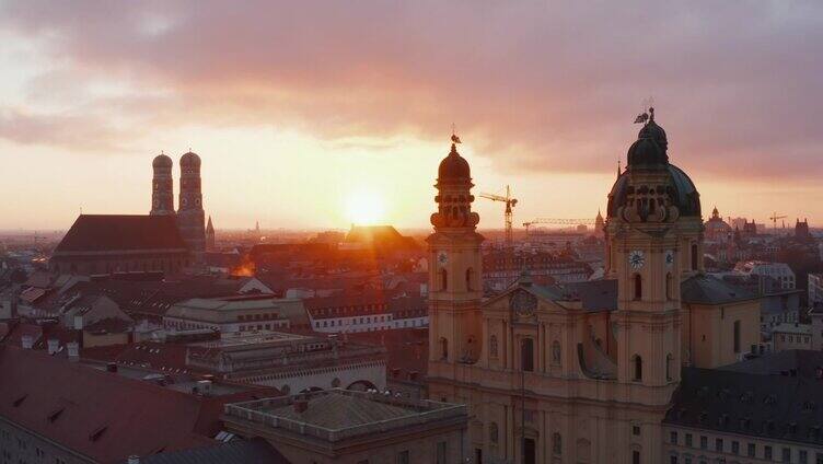 在黄金时间，空中滑梯通过令人惊叹的黄色剧院教堂大教堂建筑，夕阳下，远处的慕尼黑城市景观
