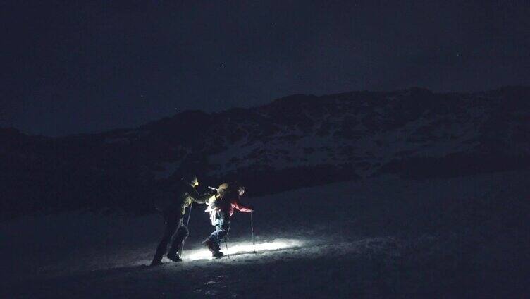 登山运动员在黎明攀登雪山脊