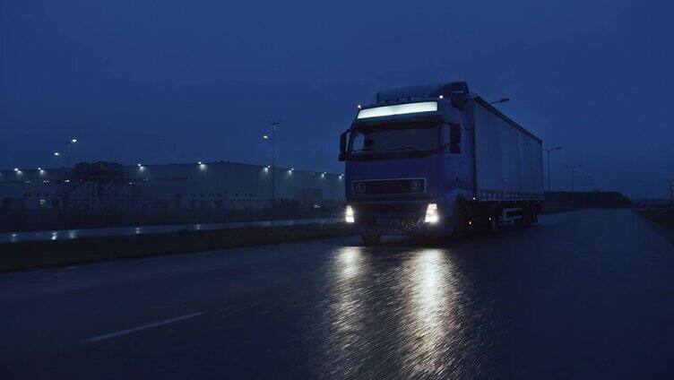 长途半卡车在晚上的高速公路上陆穿过雨