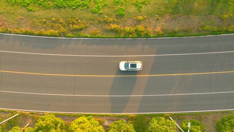 夕阳下白色车行驶在公路航拍