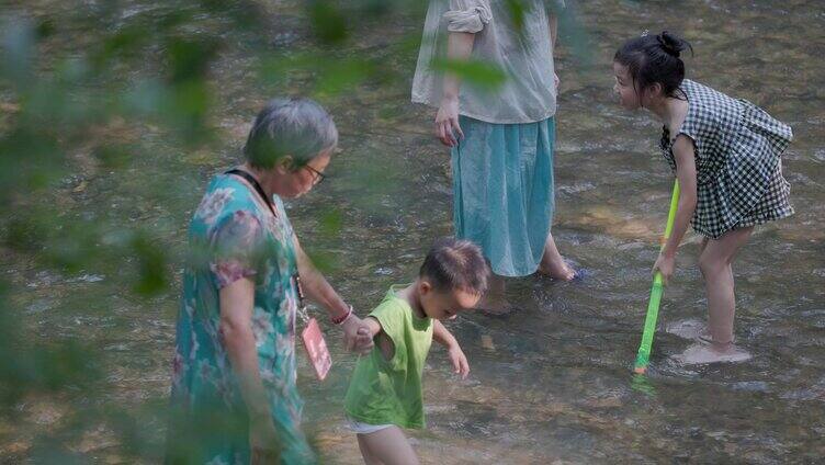 家长带着女儿在水里玩水枪滋水