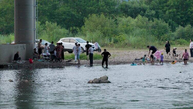 大桥下的小溪流水里玩水嬉戏的人群