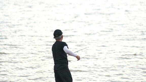 江边河滩一名黑色衣服孤独的钓鱼人