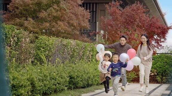 父母带着孩子举气球奔跑快乐童年