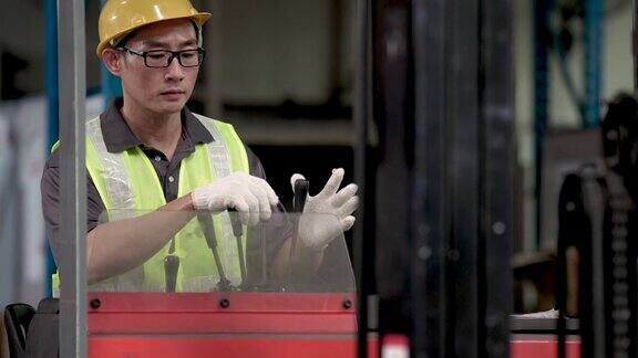 亚洲华人仓库工人使用叉车在工业工厂搬运货物