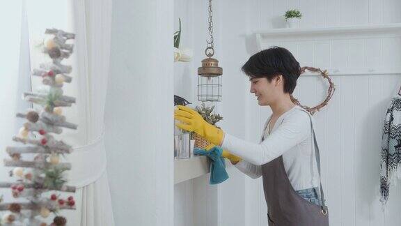 一名亚洲妇女戴着清洁手套用酒精喷雾消毒剂清洁房屋