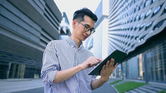 亚洲商人在城市街道上使用平板电脑