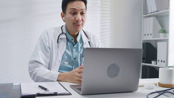 成熟的亚洲男性医生使用笔记本电脑视频通话的医疗结果在咨询患者在健康诊所