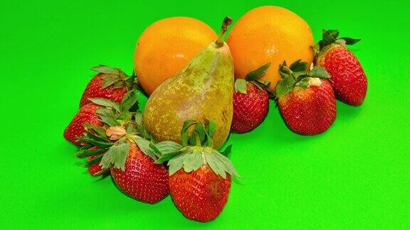 绿色背景上的草莓、梨和橙子