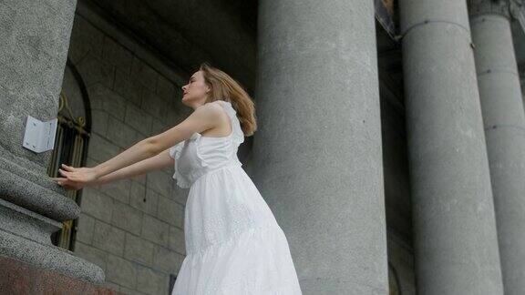 身穿白色礼服的年轻芭蕾舞者在剧院的楼梯上慢动作舞蹈芭蕾舞者做反向的腿秋千4k120fpsProresHQ