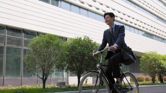 英俊的年轻商人骑着自行车展望未来