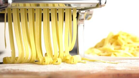 在意大利面切割机上生产意大利面新鲜的手工意大利面从机器里出来靠近在切面团的机器上制作传统的意大利自制面食